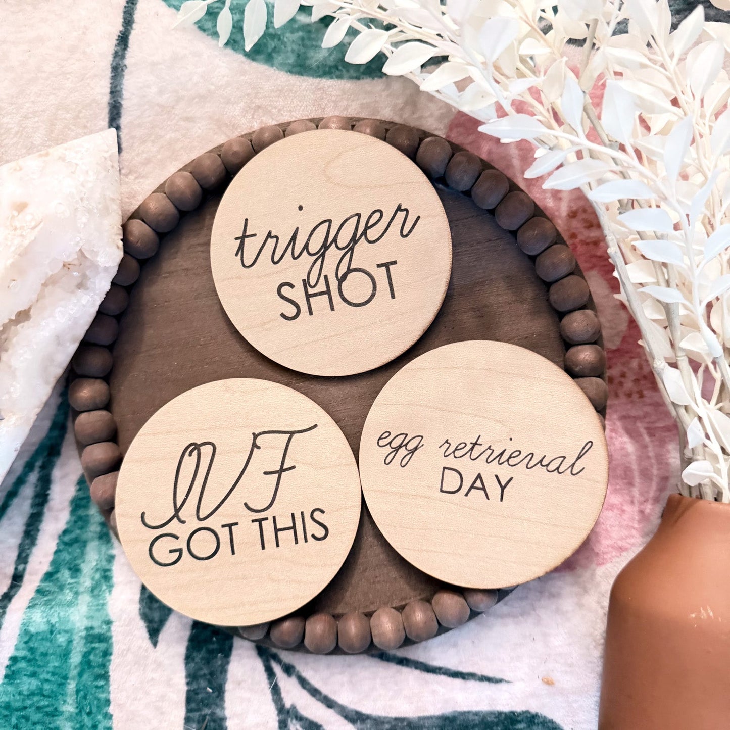 Three wooden discs with engraved text on a decorative surface with flowers.