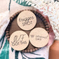 Three wooden discs with engraved text on a decorative surface with flowers.