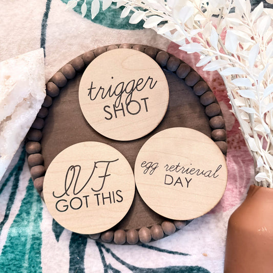 Three wooden discs with engraved text on a decorative surface with flowers.